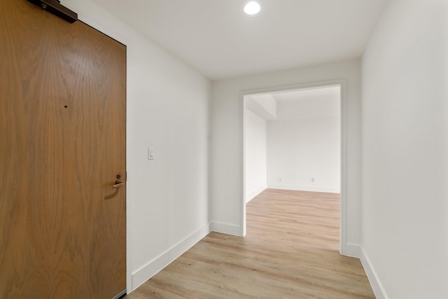 hall with baseboards, recessed lighting, and light wood finished floors