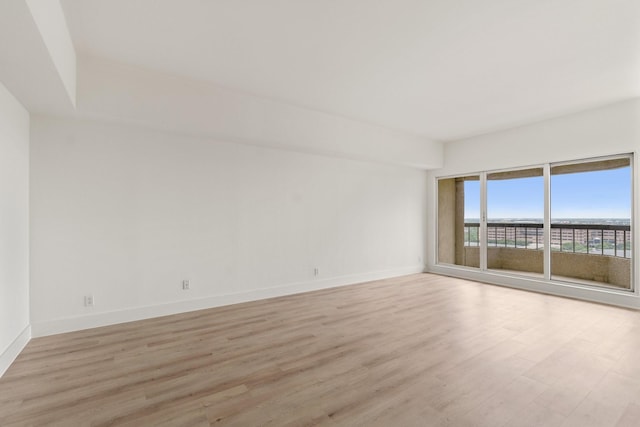 empty room featuring light wood-type flooring and baseboards