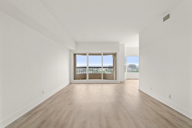 empty room featuring baseboards, visible vents, and light wood-style flooring