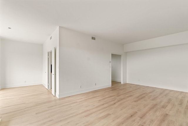 empty room with light wood-style floors, baseboards, and visible vents