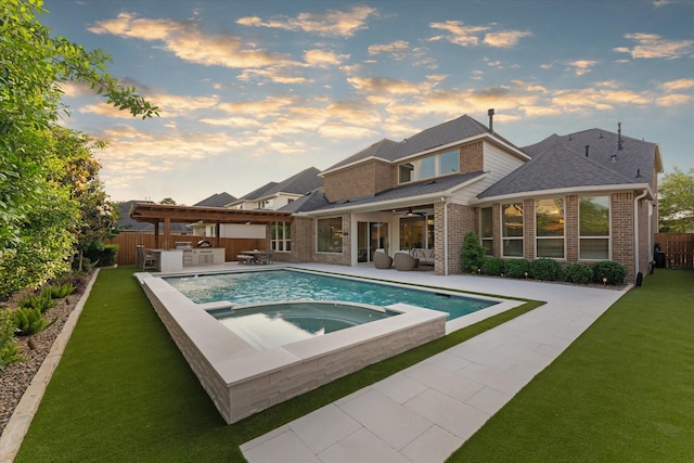 pool at dusk with fence, a patio, a ceiling fan, a lawn, and an in ground hot tub