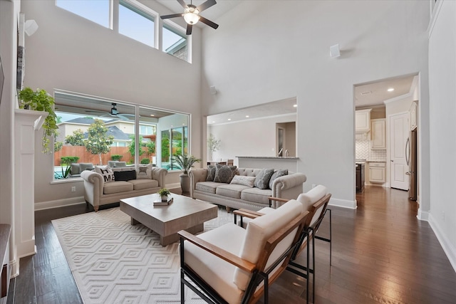 living room with a ceiling fan, dark wood-style flooring, and a towering ceiling