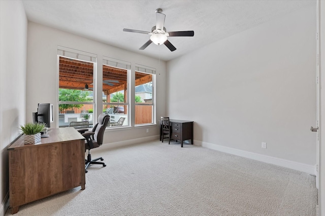 office space with baseboards, ceiling fan, and light colored carpet