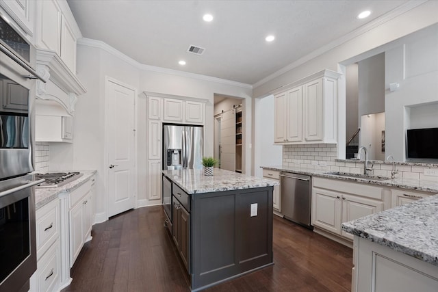 kitchen with white cabinetry, appliances with stainless steel finishes, a sink, and tasteful backsplash