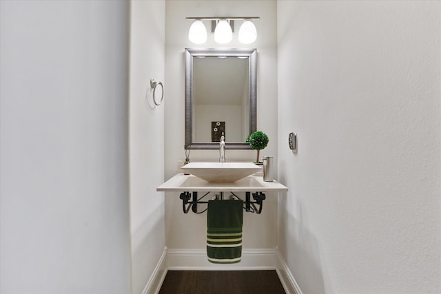 bathroom with baseboards, a sink, and wood finished floors