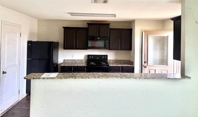 kitchen with visible vents, dark brown cabinetry, light stone counters, and black appliances