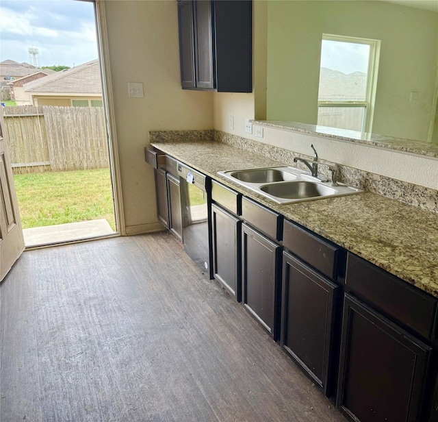 kitchen featuring wood finished floors, a sink, dishwasher, and a healthy amount of sunlight