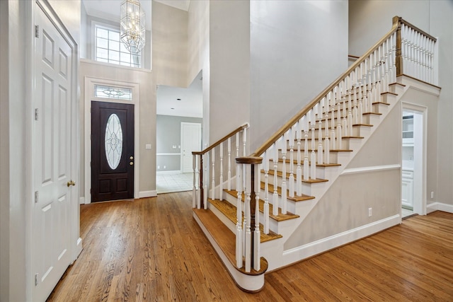 foyer with wood finished floors, baseboards, a high ceiling, and stairway