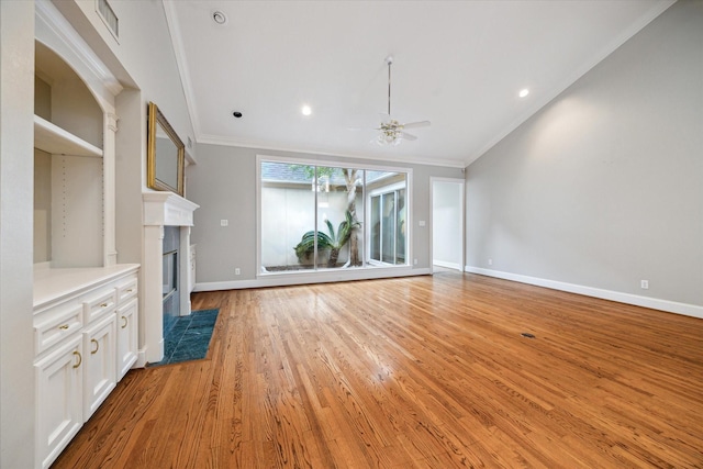 unfurnished living room with crown molding, ceiling fan, light wood-style flooring, baseboards, and a high end fireplace