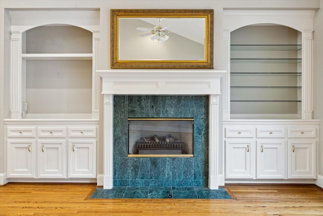 details featuring ceiling fan, built in features, wood finished floors, and a high end fireplace