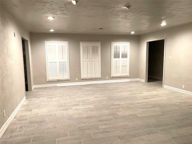 unfurnished room with baseboards, recessed lighting, and light wood-type flooring