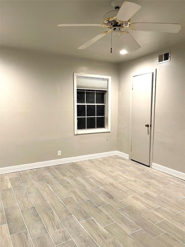 empty room featuring baseboards, ceiling fan, light wood finished floors, and visible vents