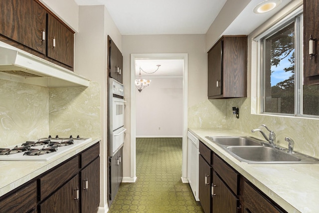 kitchen featuring a sink, baseboards, tile patterned floors, light countertops, and white appliances