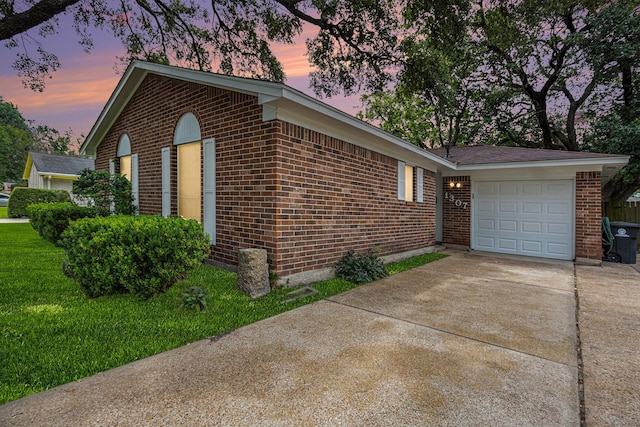 view of home's exterior featuring concrete driveway, brick siding, and a yard