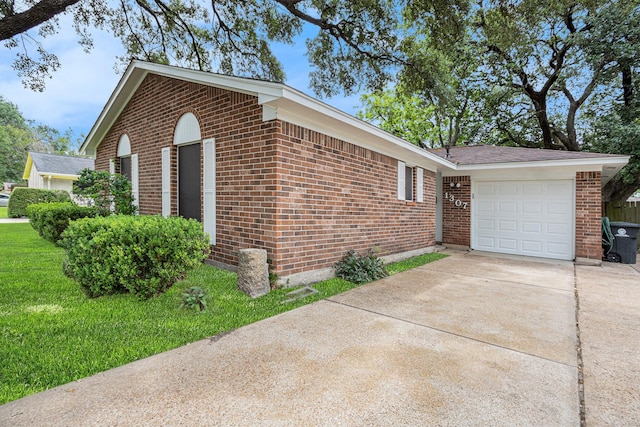 view of home's exterior featuring a lawn, brick siding, and concrete driveway