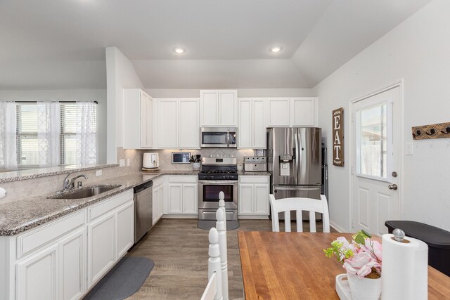 15727 Ty Cobb Ct, Splendora, TX 77372 - kitchen featuring wood finished floors, light stone countertops, a sink, appliances with stainless steel finishes, and backsplash