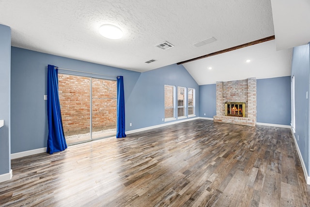 unfurnished living room featuring a textured ceiling, baseboards, visible vents, and wood finished floors
