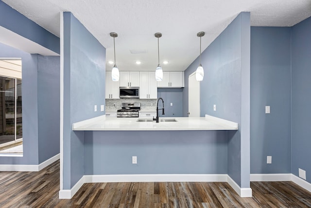 kitchen with decorative backsplash, a sink, baseboards, a peninsula, and stainless steel appliances