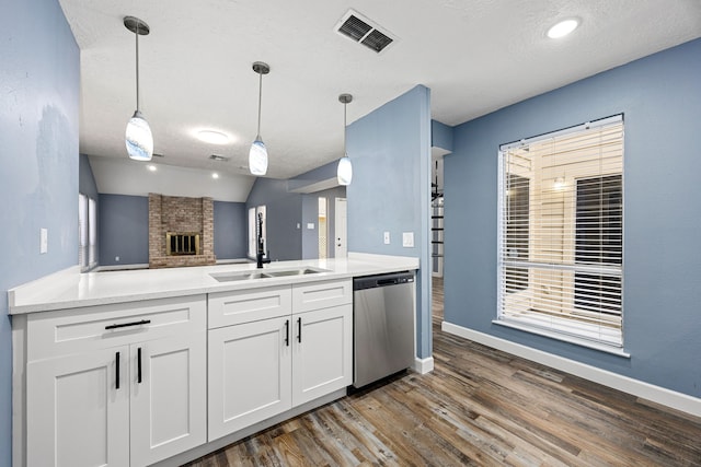 kitchen with a sink, dishwasher, dark wood finished floors, a peninsula, and visible vents