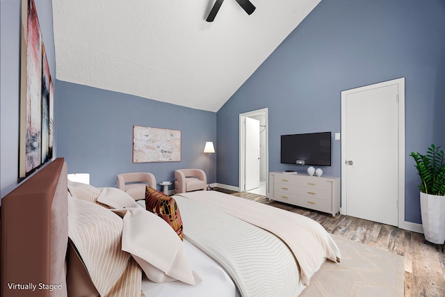bedroom featuring baseboards, a ceiling fan, wood finished floors, and high vaulted ceiling