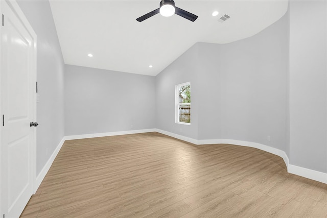 spare room with ceiling fan, visible vents, light wood-style flooring, baseboards, and vaulted ceiling