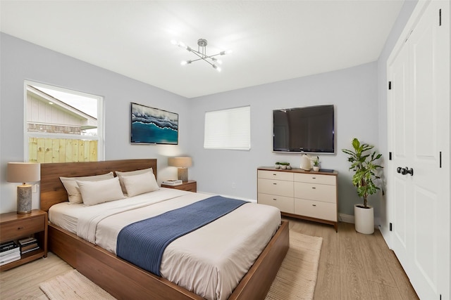 bedroom featuring baseboards, a chandelier, and light wood-type flooring