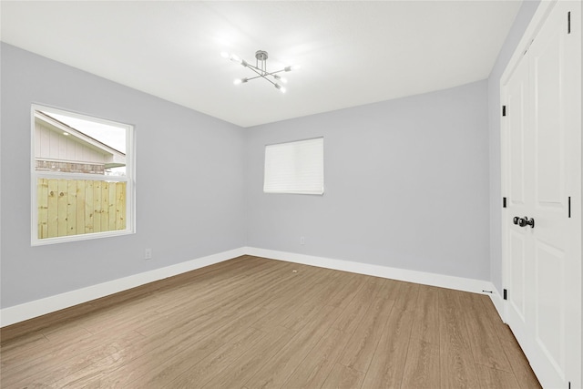 unfurnished bedroom with baseboards, a closet, wood finished floors, and a notable chandelier