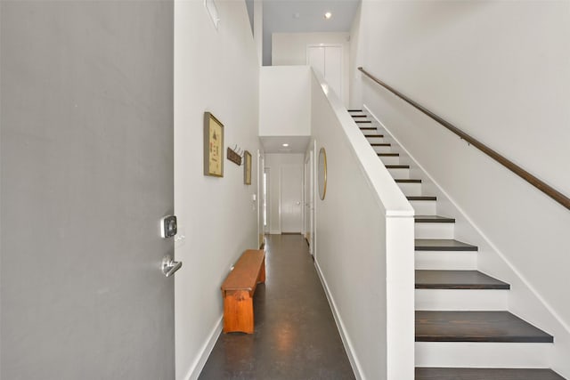 stairway with baseboards, a high ceiling, and concrete floors