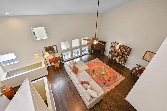 living room featuring ceiling fan, recessed lighting, wood finished floors, a towering ceiling, and a skylight