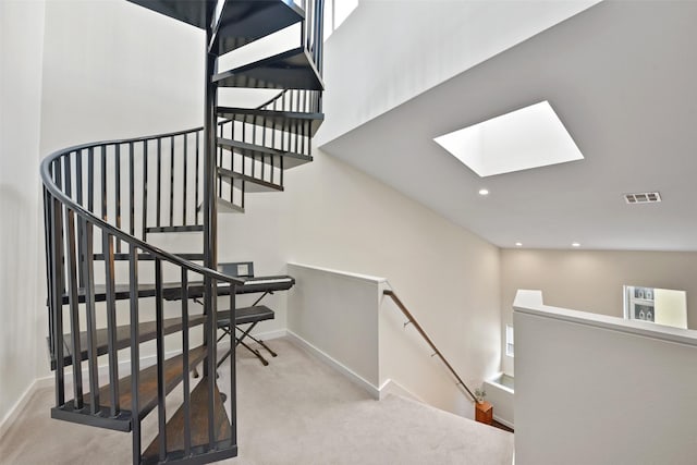 staircase featuring visible vents, a skylight, carpet floors, baseboards, and recessed lighting