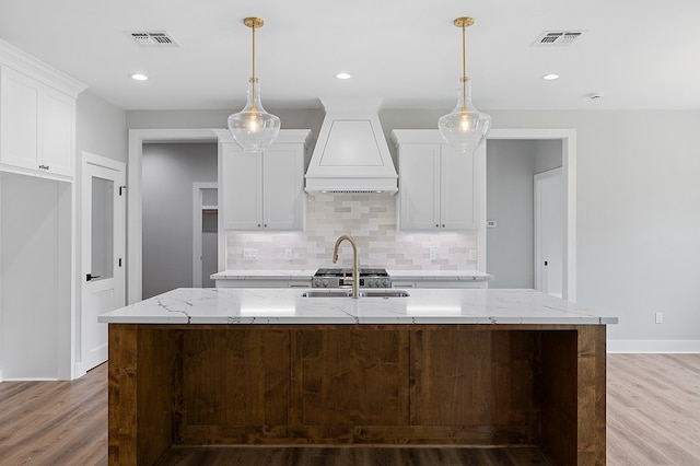 102 Tekla St, Weimar, TX 78962 - kitchen featuring visible vents, custom range hood, a sink, and light wood finished floors