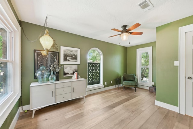 sitting room with baseboards, a wealth of natural light, light wood finished floors, and visible vents