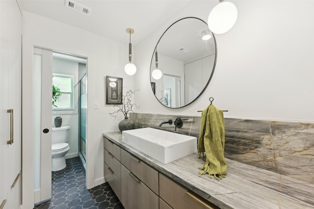 bathroom with visible vents, vanity, toilet, baseboards, and a stall shower