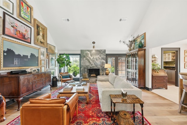 living room featuring visible vents, a high end fireplace, wood finished floors, and high vaulted ceiling