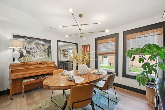dining space featuring light wood-type flooring, baseboards, a chandelier, and visible vents