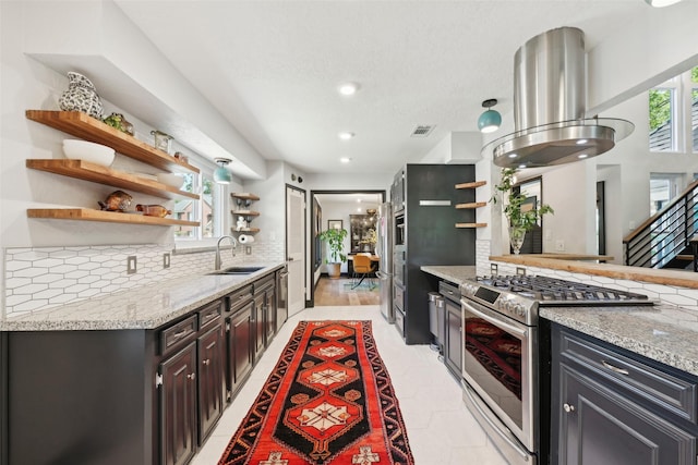kitchen featuring open shelves, tasteful backsplash, light stone counters, a sink, and appliances with stainless steel finishes