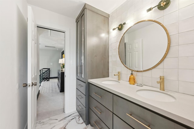 full bathroom with double vanity, a sink, marble finish floor, and decorative backsplash