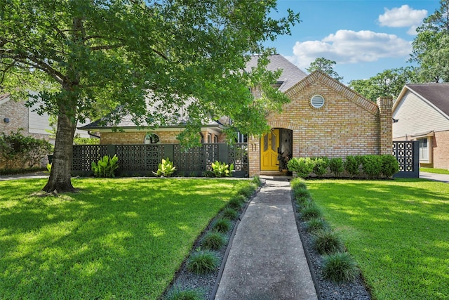 view of front of property featuring brick siding, fence, and a front yard