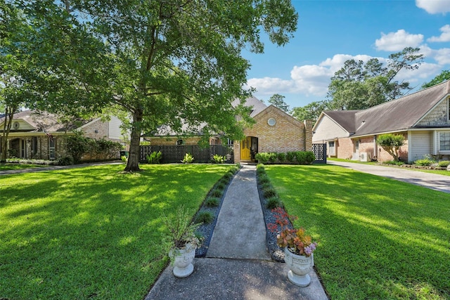 view of front of home featuring brick siding, fence, and a front yard