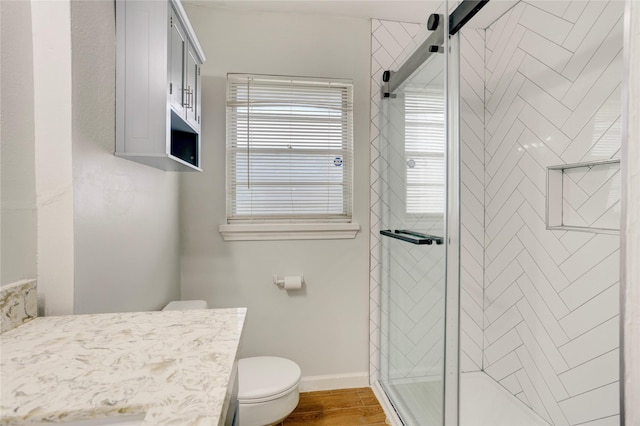 full bath featuring vanity, wood finished floors, toilet, baseboards, and a stall shower