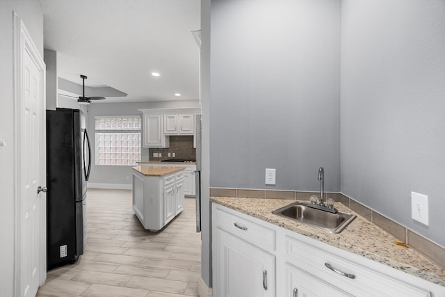 6542 Shinnecock Hills Dr, Houston, TX 77069 - kitchen with a sink, freestanding refrigerator, tasteful backsplash, a ceiling fan, and white cabinetry