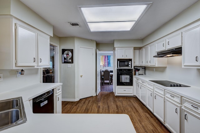 kitchen with white cabinets, black appliances, dark wood-style flooring, and under cabinet range hood
