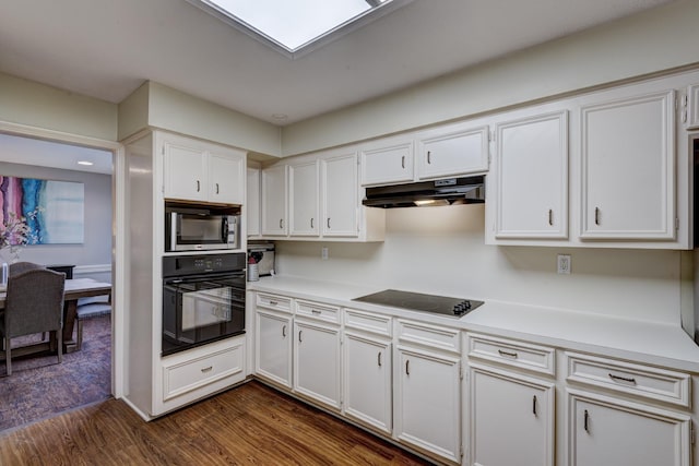 kitchen with light countertops, black appliances, under cabinet range hood, white cabinetry, and dark wood-type flooring