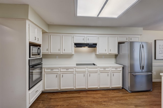 kitchen with dark wood finished floors, light countertops, white cabinets, black appliances, and under cabinet range hood