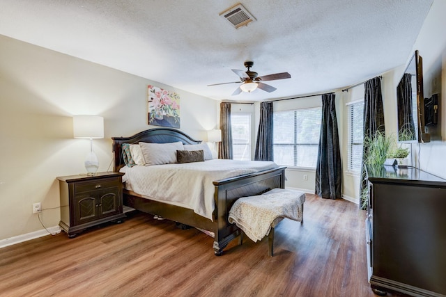 bedroom featuring a textured ceiling, baseboards, visible vents, and light wood-style floors