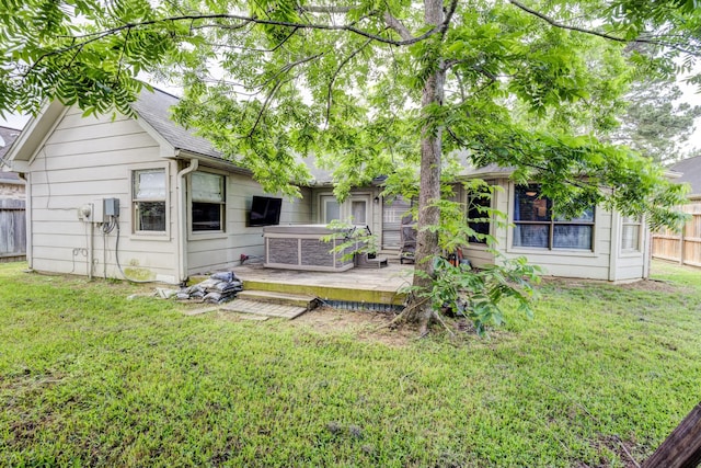 back of house featuring a lawn, a shingled roof, a jacuzzi, and fence