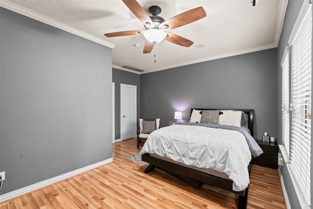 bedroom featuring crown molding, baseboards, visible vents, and wood finished floors