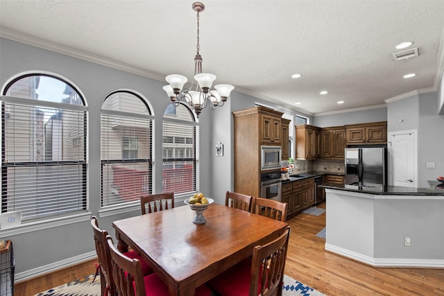 dining room featuring an inviting chandelier, crown molding, light wood-style floors, and recessed lighting