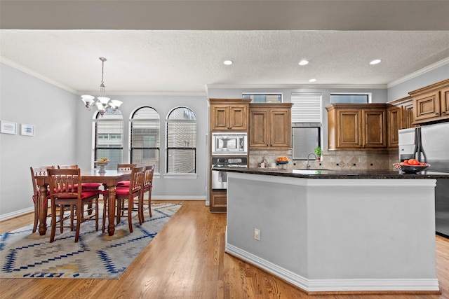 kitchen with a notable chandelier, appliances with stainless steel finishes, dark countertops, and light wood finished floors