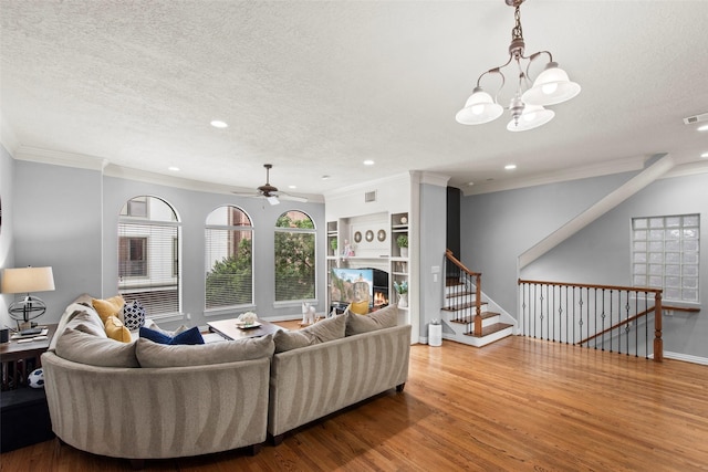 living area featuring a textured ceiling, ceiling fan with notable chandelier, recessed lighting, wood finished floors, and ornamental molding
